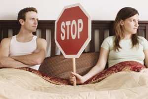 Couple holding stop sign in bed