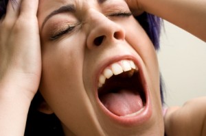 woman holding head and screaming out loud