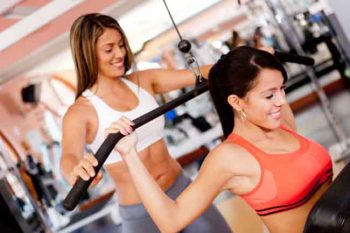 Hispanic woman working with trainer in gym